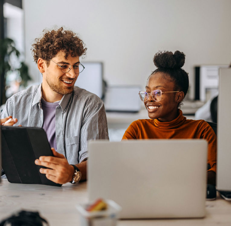 To kolleger på kontor, der samarbejder om arbejdsstyring, vagtplanlægning og tidsregistrering ved hjælp af digitale værktøjer