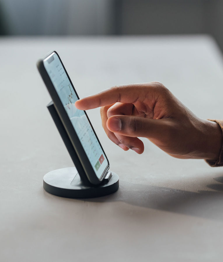 Nærbillede af en hånd, der bruger en smartphone til arbejdsstyring, vagtplanlægning og tidsregistrering
