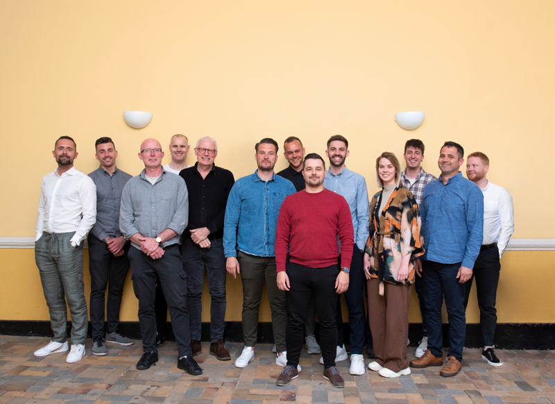 Teamfoto af medarbejdere, der arbejder med workforce management, vagtplanlægning og tidsregistrering for effektiv bemanding og drift.