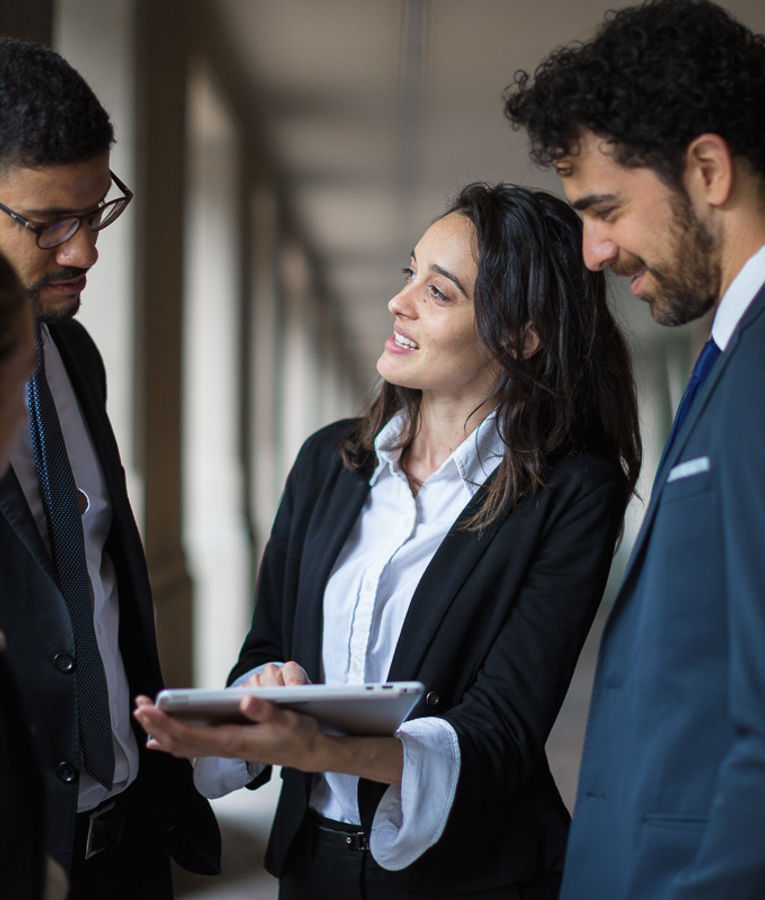 En leder præsenterer data på en tablet for sit team i jakkesæt – effektiv planlægning og overblik over tidsregistrering i professionelle arbejdsgange.