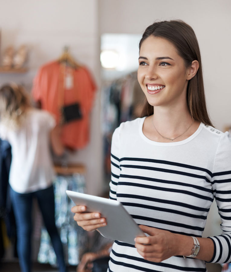En selvsikker butikschef i en tøjbutik gennemgår lagerbeholdningen og samarbejder med medarbejdere for at optimere driften.