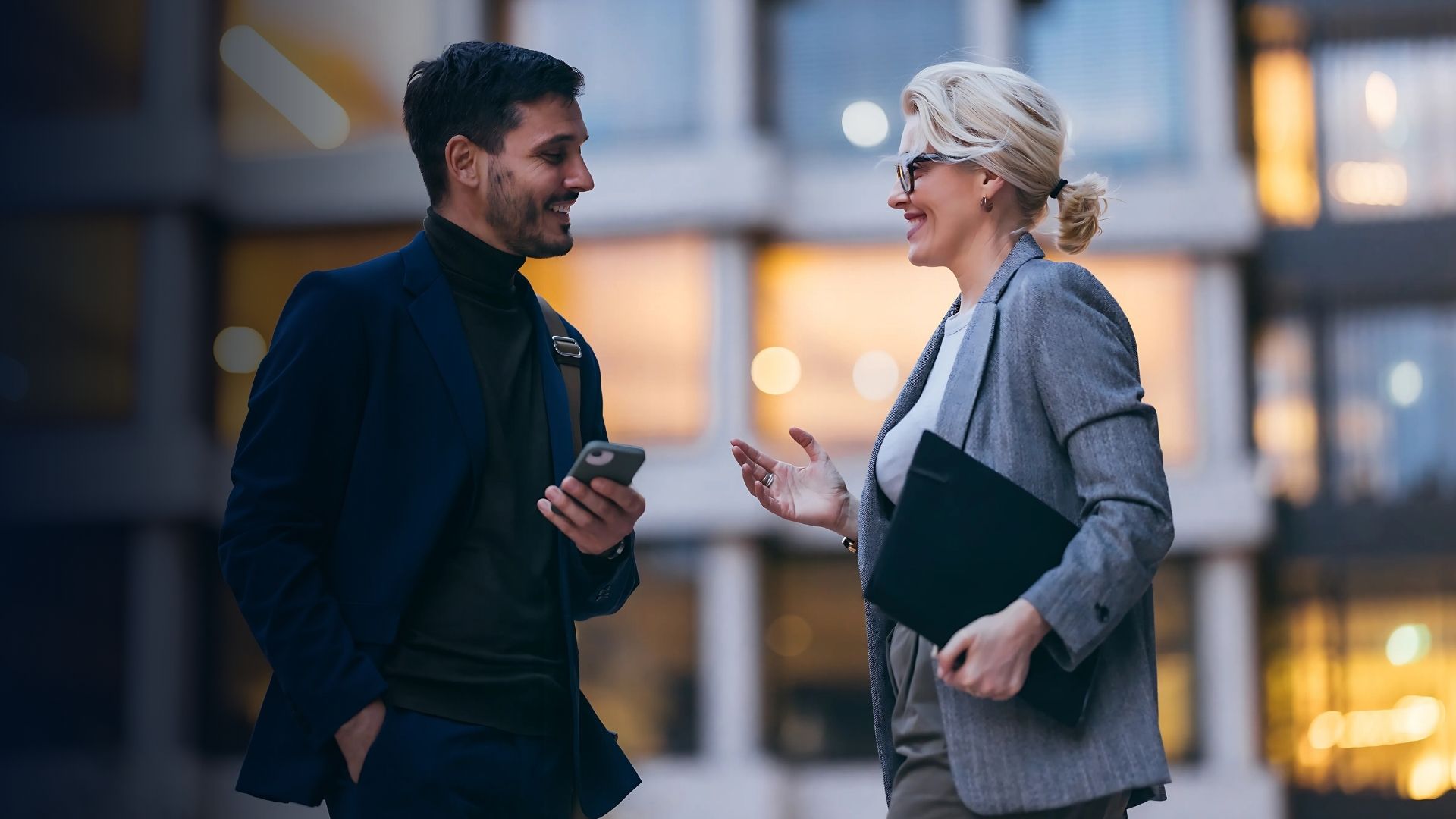 To kolleger i forretningsmiljø, der diskuterer arbejdsplanlægning og effektiv medarbejderstyring ved hjælp af en mobil enhed.