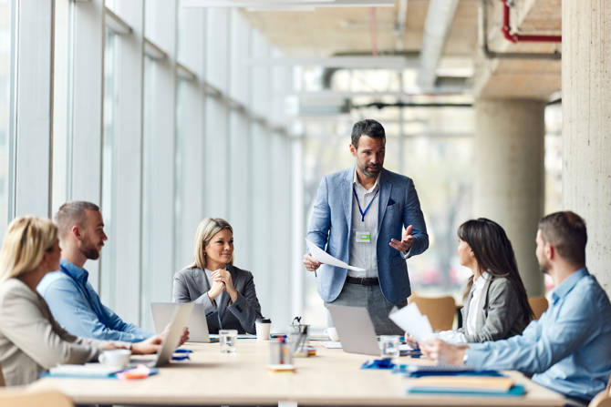 Leder holder møde med sit team om implementering af AI-baseret workforce management for bedre vagtplanlægning, tidsregistrering og optimering af arbejdsstyrken.