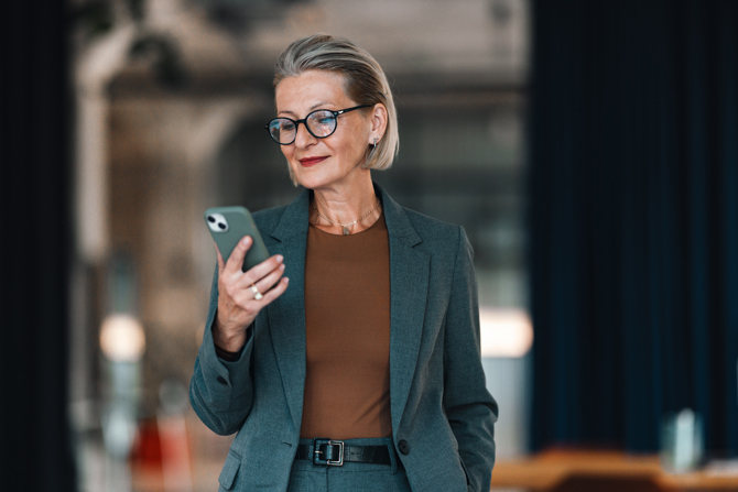Leder tjekker vagtplan og tidsregistrering på sin smartphone via en AI-drevet workforce management løsning, der giver overblik over medarbejdere og planlægning.