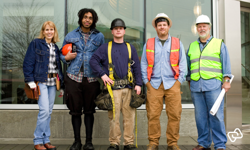 Gruppe af medarbejdere i forskellige roller og sikkerhedsudstyr, som illustrerer behovet for præcis vagtplanlægning, bemandingsstyring og effektiv workforce management på tværs af teams.