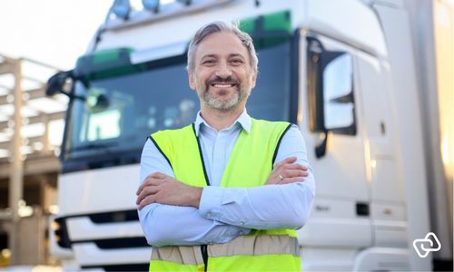 Logistikmedarbejder står foran lastbil på terminalen, hvor digital vagtplanlægning i logistikbranchen sikrer overholdelse af hviletidsregler, korrekt bemanding og effektiv drift.