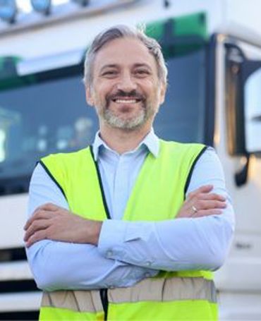 Logistikmedarbejder står foran lastbil på terminalen, hvor digital vagtplanlægning i logistikbranchen sikrer overholdelse af hviletidsregler, korrekt bemanding og effektiv drift.