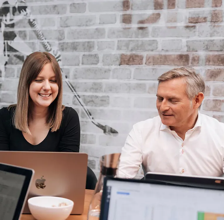 Software4You-teamet samarbejder ved laptops under et møde og gennemgår HR-data og planlægningsværktøjer integreret med Timegrip til optimering af workforce.