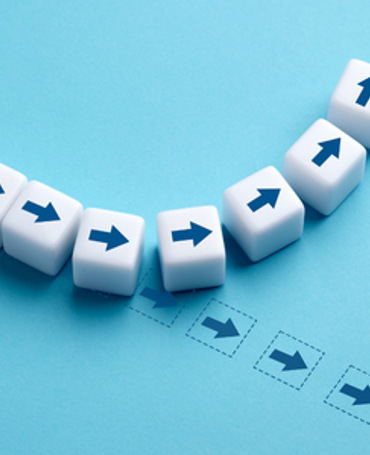 Illustration af små klodser med pile, hvor én klods skifter retning, som symbol på øget løngennemsigtighed, gennemsigtige lønstrukturer og datadrevet HR-styring.