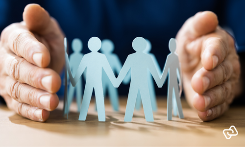 Personaleikoner beskyttet af to hænder som symbol på effektiv vagtplanlægning, bemandingsstyring og optimering af ressourcer i moderne workforce management.