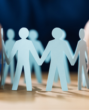 Personaleikoner beskyttet af to hænder som symbol på effektiv vagtplanlægning, bemandingsstyring og optimering af ressourcer i moderne workforce management.